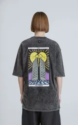 Remera negra con efecto nevado, de corte oversize y manga corta. Estampado en la espalda con diseño de la carta del tarot 'La Torre'.