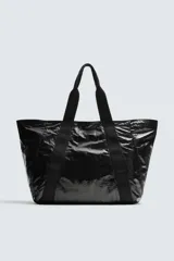 Bolso tipo shopper negro con acabado metalizado. Tiene un compartimento principal con cierre de cremallera y un bolsillo interior de malla con cremallera.