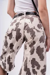 Bermuda de jean color beige con estampado de manchas marrones tipo vaca, tiro alto, corte ancho y largo a la rodilla.