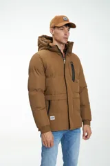 Campera puffer color marrón con capucha no desmontable, cierre frontal con cremallera y botones a presión, bolsillos laterales y bolsillo en el pecho con cierre.