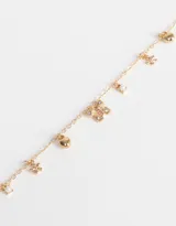 Pulsera dorada con cadena de eslabones y cierre de mosquetón. Incluye dijes colgantes de mariposa con strass, corazón, flor, perla y trébol.