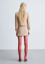 Minifalda color beige con botones plateados al frente y cierre lateral invisible.