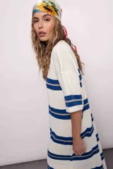 Vestido largo tejido a rayas horizontales azules y beige sobre fondo blanco, con mangas cortas y tajos laterales.