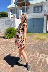 Vestido corto con estampado abstracto en tonos rosa, beige, negro y rojo. Tiene escote cuadrado, breteles anchos con volados y corte holgado.