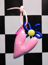 Llavero con dije de corazón acolchado rosa, flor azul con centro amarillo y cinta de agarre rosa.