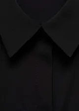 Camisa negra de tejido fluido, corte recto, cuello camisero, manga larga con puños abotonados y cierre frontal con botones.