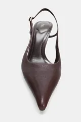 Zapato de tacón alto fino tipo slingback en piel color bordó. Presenta un diseño con acabado en punta, escote redondo y tira ajustable con hebilla metálica en el lateral.
