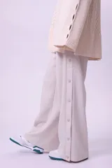Pantalón de vestir color beige, de corte palazzo y tiro alto, con cierre lateral con botón y cremallera.