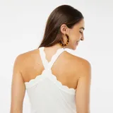 Camiseta de tirantes blanca con cuello halter cruzado y detalle de volados en el escote.