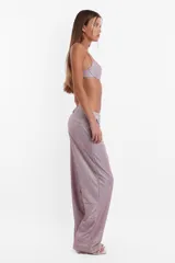 Pantalón de tela glitter color lila, de corte sastrero clásico y tiro medio. Tiene pasacinto, cierre con gancho metálico y cierre en cartera, bolsillos laterales diagonales y bolsillos traseros ribete falsos.