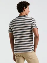 Remera de manga corta con rayas horizontales en tonos beige, marrón y azul marino. Cuello redondo a contratono azul marino y logo bordado en el pecho.