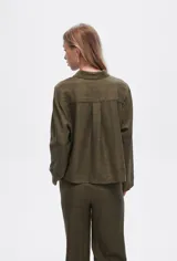 Camisa color natural de poliéster con cuello camisero, cierre con botones, dos bolsillos frontales y corte ancho.