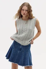 Chaleco tejido gris melange con diseño de ochos, cuello redondo y sisas amplias. Confeccionado en algodón y acrílico.