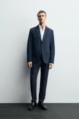 Pantalón de vestir azul marino, de corte slim fit, con bolsillos laterales y traseros. Se ajusta a la cintura con cinturón de cuero marrón.