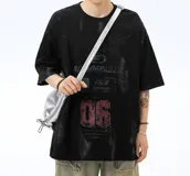 Remera negra de corte oversize con efecto tie-dye o desteñido en tonos grises. Presenta un estampado frontal grande con tipografía estilo metal/rock, el número "06" en rojo y texto en inglés.