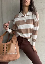 Buzo de tejido de punto color beige con rayas horizontales blancas, cuello polo con botones y mangas largas.