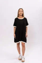 Vestido corto negro de tejido de punto calado, con cuello redondo y mangas cortas con ribete blanco.