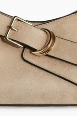 Cartera color beige con correa ajustable, cierre magnético oculto y trabilla decorativa con hebilla de metal dorada. La correa tiene un extremo extralargo para poder usar como bandolera.
