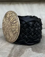 Cinto faja negro trenzado con hebilla dorada circular con diseño.