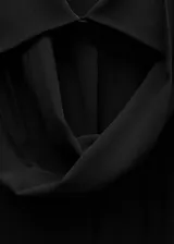 Camisa negra de tejido fluido semitransparente, con cuello camisero, lazo en el cuello, manga larga con puños abotonados, diseño recto, bajo con aberturas laterales y cierre delantero con botones.