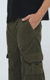Pantalón cargo de corderoy color verde militar, de calce regular y diseño unisex. Presenta cintura elástica, bolsillos laterales y bolsillos tipo cargo con solapa en los laterales de las piernas.