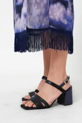Vestido largo con estampado abstracto en tonos azules, violetas y grises. Tiene cuello mao con abertura en forma de gota, mangas largas acampanadas con detalle de botón en los puños, espalda abierta, tajo frontal y flecos en el ruedo.