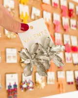 Aretes colgantes grandes con forma de flor, de metal plateado con acabado texturizado y brillante.