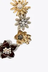 Collar dorado con dije de flores metálicas con brillos y joyas de diferentes colores.