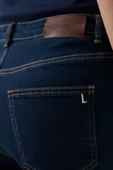 Pantalón de jean azul oscuro, de corte recto, con tajos en el ruedo.