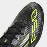 Championes de fútbol Adidas F50 League para césped artificial, color negro con detalles en amarillo y plateado. Presentan exterior Fiberskin con estampado Sprintgrid y lengüeta Tunnel adaptable.