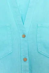 Camisa de lino color celeste claro, con cuello solapa, escote pico, manga corta con vuelta y dos bolsillos de plastrón en el delantero. Cierre frontal con botones.
