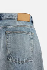 Pantalón de jean gris de corte recto, con cinco bolsillos, efecto lavado y cierre frontal con botones.