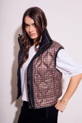 Chaleco negro acolchado con cierre frontal y cuello alto. Diseño reversible con cordones ajustables en la cintura.