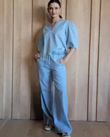 Conjunto de camisa y pantalón de lino blanco. La camisa es de manga larga y se ata en la parte delantera. El pantalón es de corte ancho y tiene cordón en la cintura.