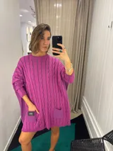 Sweater negro de punto con diseño de trenzas, corte holgado, mangas largas y bolsillos frontales. Tejido artesanalmente en Uruguay, con puños altos ajustados.
