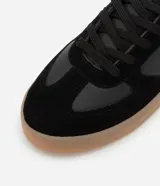 Championes urbanos de corte bajo, color blanco con detalles en gris y negro. Confeccionados en material sintético con recortes efecto gamuza y suela de látex color caramelo.
