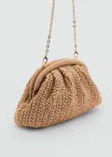 Bolso de mano tipo clutch color beige, tejido en fibra natural. Tiene asa larga desmontable para usar como bandolera, cierre a presión y forro interior.