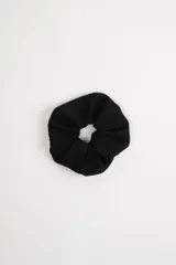 Scrunchie negro de tela con textura pointelle.
