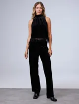 Conjunto de musculosa y pantalón en terciopelo negro, marca Julia Jordan. Blusa de cuello alto y terminación de ruedo con plumas. Pantalón con cintura elastizada.