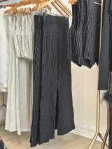 Conjunto blanco de chaleco y pantalón de vestir con finas rayas verticales. El chaleco es sin mangas, con cuello en V y cierre frontal con botones. El pantalón es de corte recto y tiro alto.