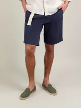 Bermuda de hombre color azul marino, marca El Ganso, de tejido 77% algodón, 20% algodón reciclado y 3% elastán. Corte Regular Fit. Tiene dos bolsillos laterales y bolsillos traseros con cintas insertadas. Tinte pigmentario consiguiendo un color desgastado.