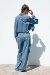 Pantalón de jean azul oscuro, de tiro medio, corte ancho y largo, estilo jogger con cintura elástica ajustable con cordones, bolsillos delanteros de vivo y bolsillos de parche en la espalda.