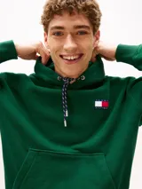 Buzo verde con capucha y cordón distintivo, bolsillo canguro, puños y bajo de punto canalé, logo oversize de Tommy Hilfiger en la manga y la parte trasera, parche con logo de Tommy Hilfiger en el pecho y detalles distintivos de Hilfiger Sailing.
