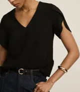 Blusa color beige con escote en pico y mangas cortas tulipán. Confeccionada en tejido de poliéster con efecto airflow (textura arrugada).