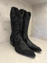 Bota tejana negra de cuero con calado y bordado en hilo blanco. Tiene caña media, punta fina y taco bajo. Fabricada artesanalmente en Uruguay.
