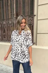 Blusa de algodón con estampado animal print de leopardo en tonos blanco y morado oscuro. Presenta cuello mao con abertura frontal y botones, y mangas cortas enrolladas con presilla.