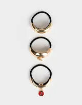 Set de tres gomitas de pelo con elástico negro y apliques metálicos dorados. Incluye una gomita con cuff liso, una con cuff y dije de cristal, y otra con cuff y dije de mariquita.