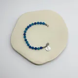 Pulsera de cuentas de piedras naturales de 6mm de diámetro, con terminaciones y dije con el símbolo del signo zodiacal en acero plateado o baño dorado.