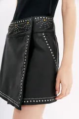 Minifalda negra cruzada de cuero ovino con apliques de tachas y piedras.