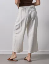 Pantalón de lino color crudo, de corte ancho y tiro alto, con bolsillos laterales y cintura elástica.